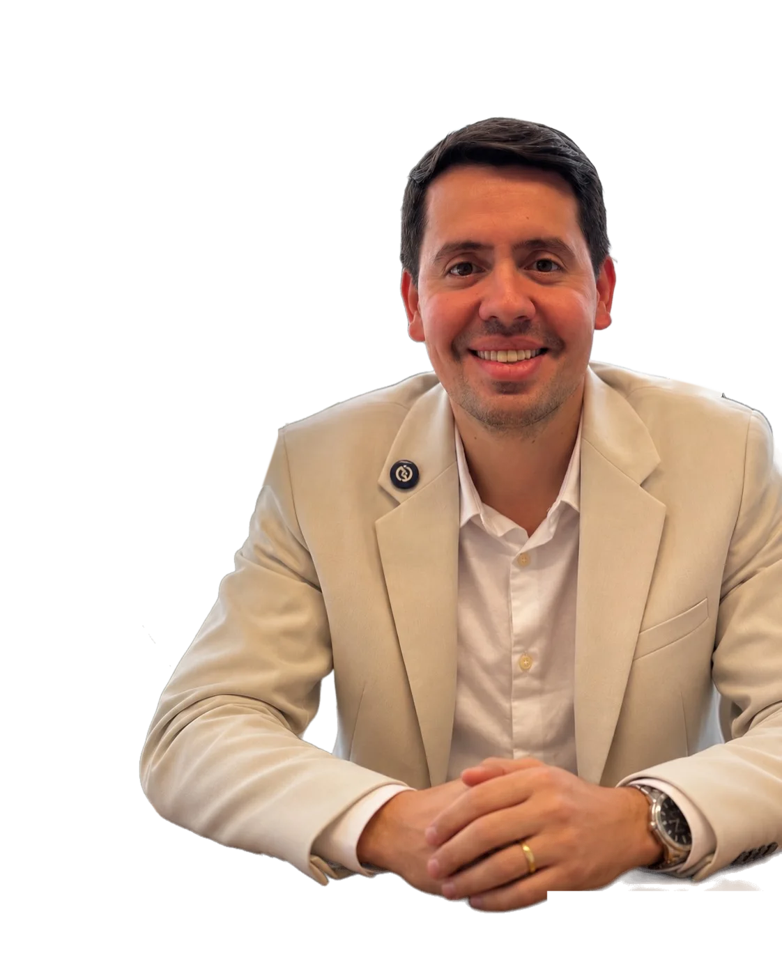 Dr. Caio Blanch sorrindo, de blazer bege, com os braços cruzados sobre a mesa